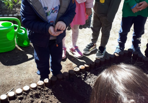 Zdjęcie przedstawia dzieci planujące czynność sadzenia nasion
